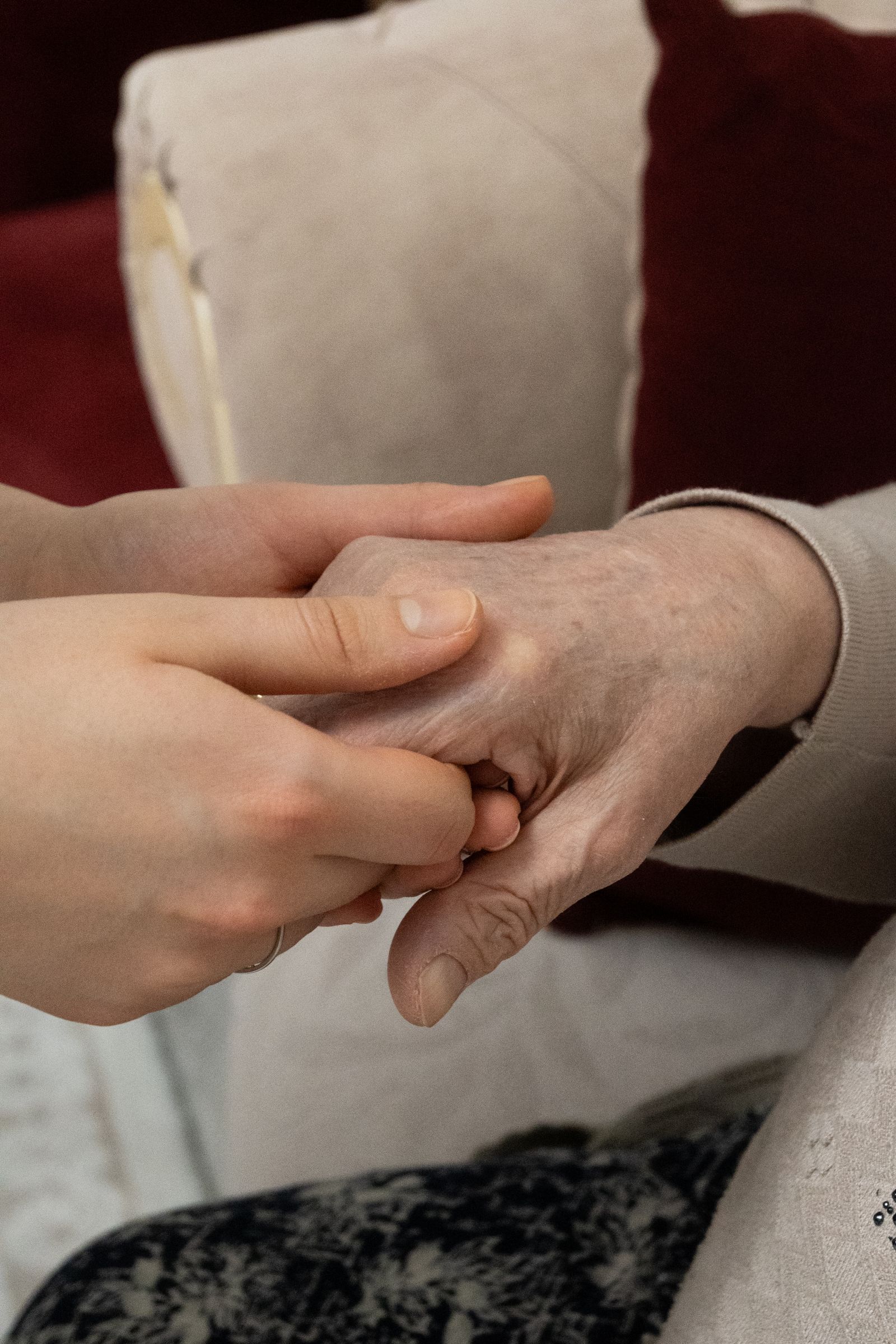 A younger person holding an older person’s hand at home